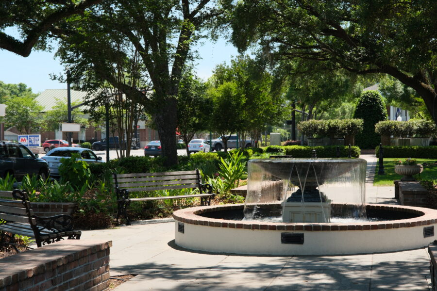Fountain in a shaded park square in Charleston with benches and greenery.
