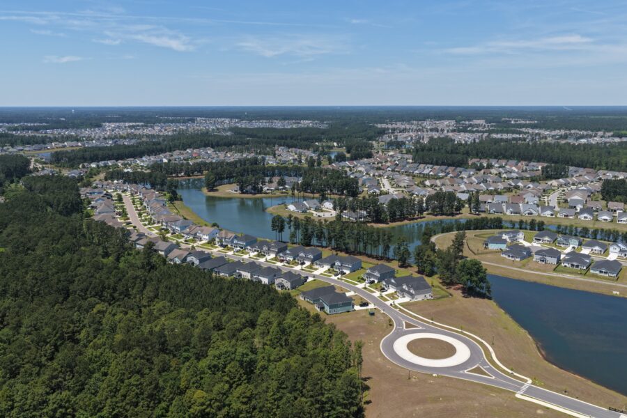 Aerial view of a suburban residential neighborhood with lakes and surrounding forest.
