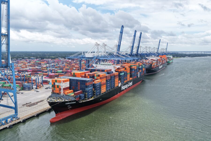 Aerial view of container ships docked at a busy port terminal with cranes.