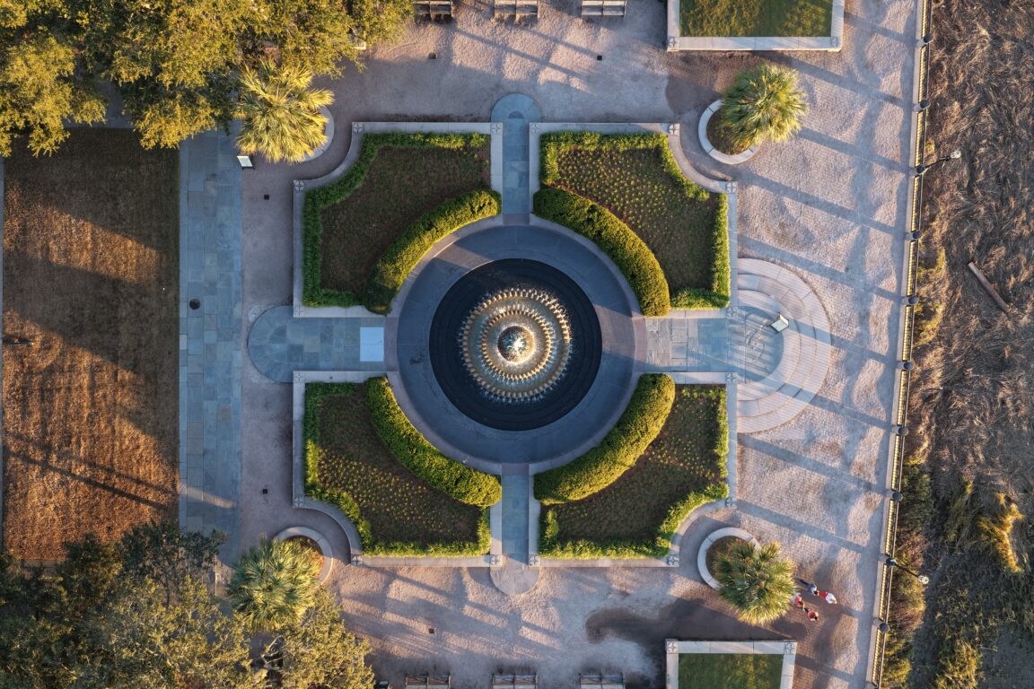 Top-down aerial view of a symmetrical formal garden with a circular fountain at its center.