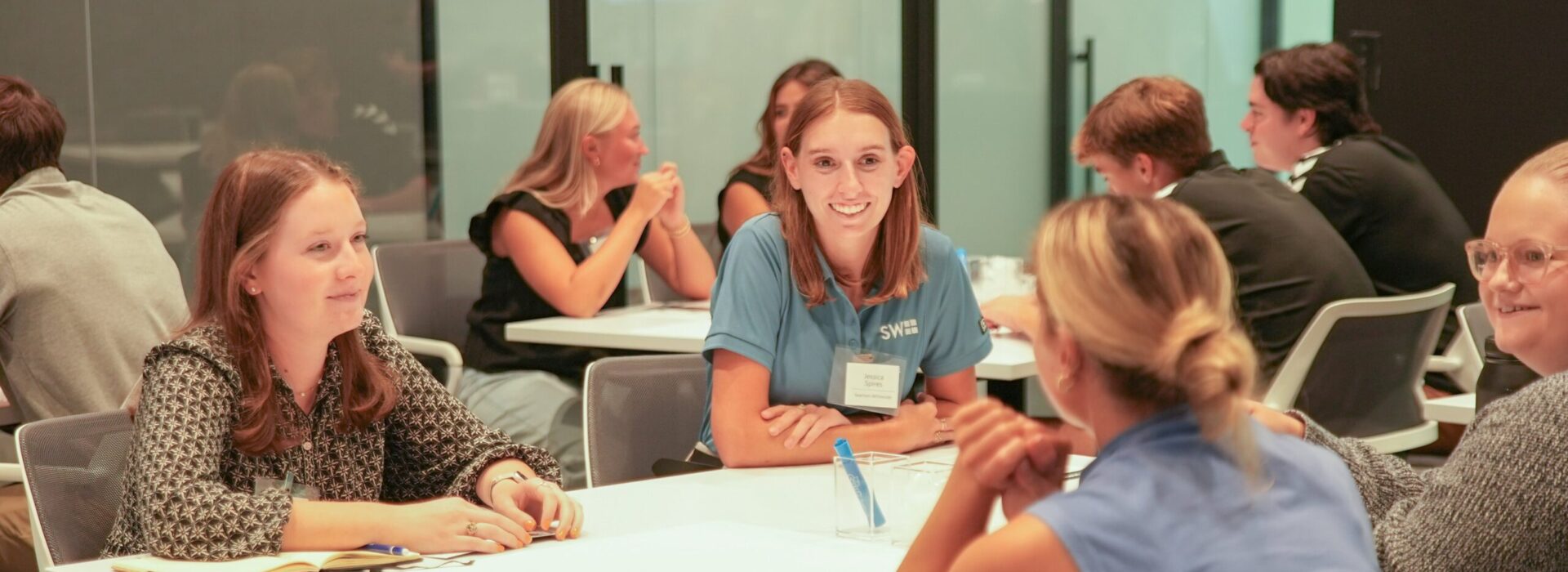 Group of women talking at tables during a networking event.
