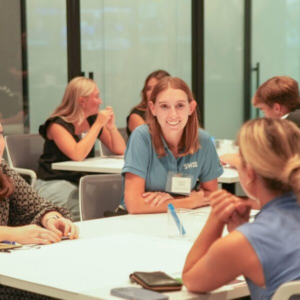 Group of women talking at tables during a networking event.