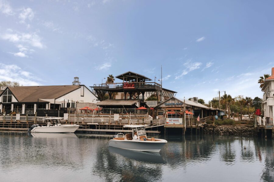 Boats on the water in front of a waterfront restaurant and marina.