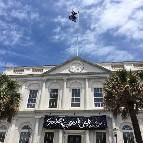 Historic white building displaying a Spoleto Festival banner under a blue sky.