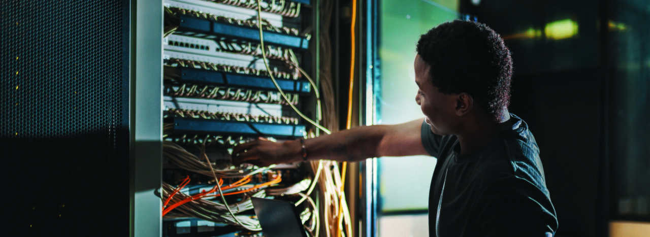 System administration, man is working in data center with laptop