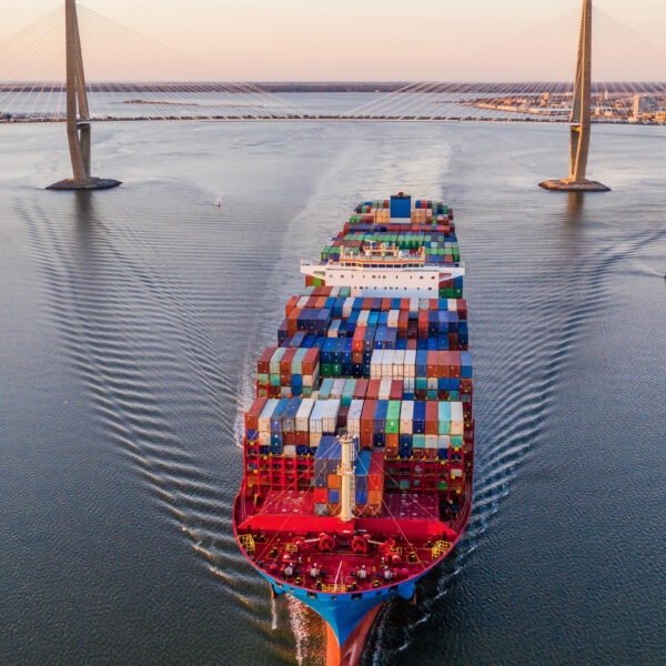 A cargo ship passes under the Ravenel Jr. Bridge in South Carolina at dusk.