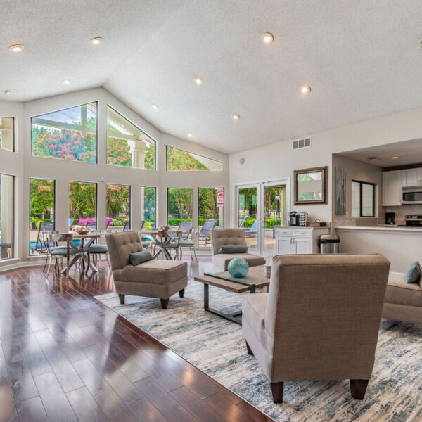 A large living room with floor-to-ceiling windows overlooking a swimming pool.