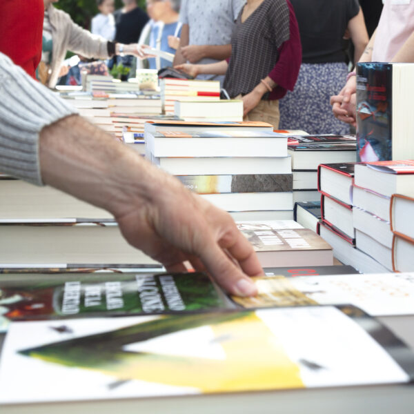 A close-up of people browsing books at an outdoor bookstore.