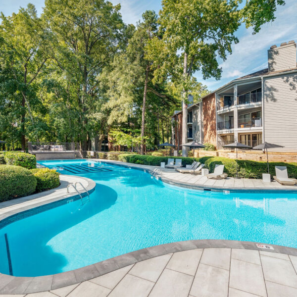 A large swimming pool in an apartment complex during the day.