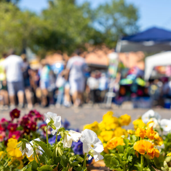 A crowd of people at a festival with flowers.