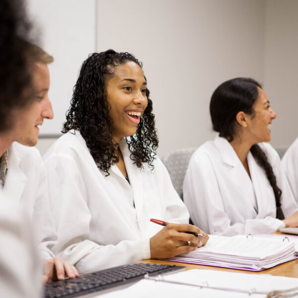 A medical student smiles while at a table with her peers.