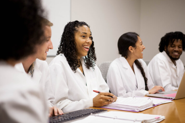 A medical student smiles while at a table with her peers.