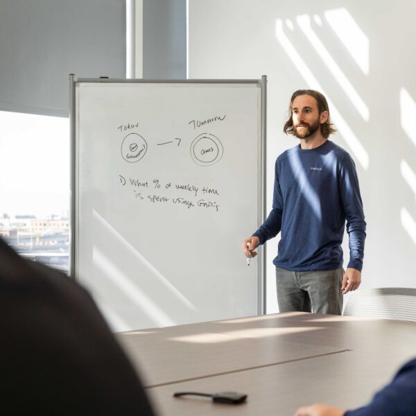 A man uses a whiteboard to give a presentation in a boardroom during the day.