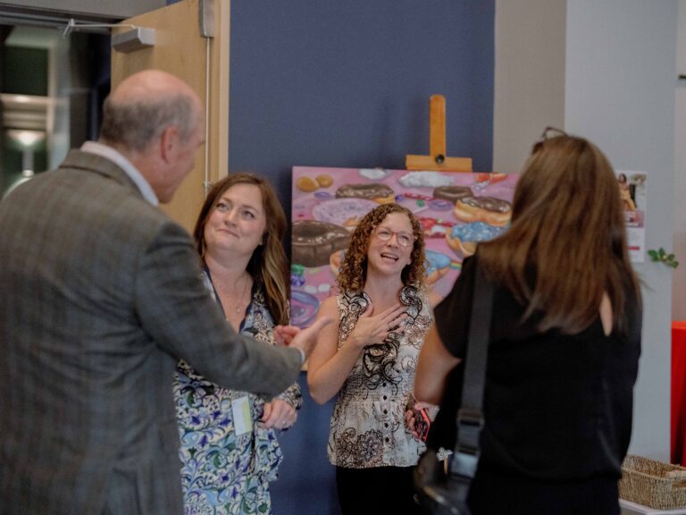 A group of coworkers smile and talk with each other.