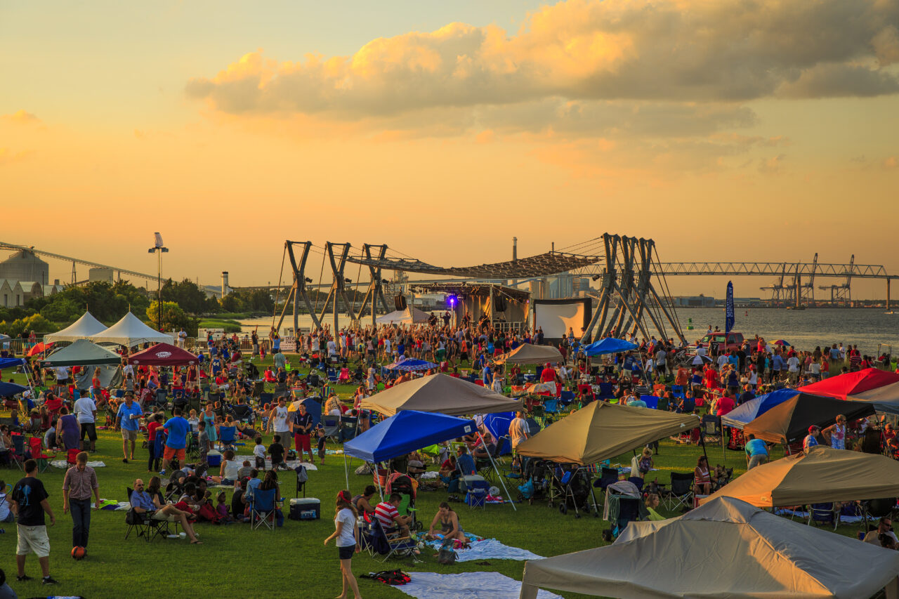 A large crowd of people at a festival in Charleston at dusk.