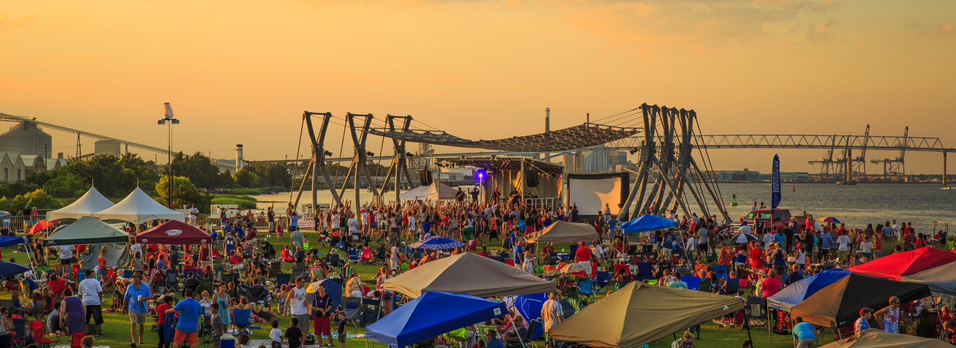 A large crowd of people at a festival in Charleston at dusk.
