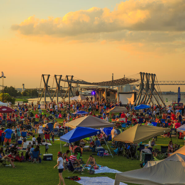 A large crowd of people at a festival in Charleston at dusk.