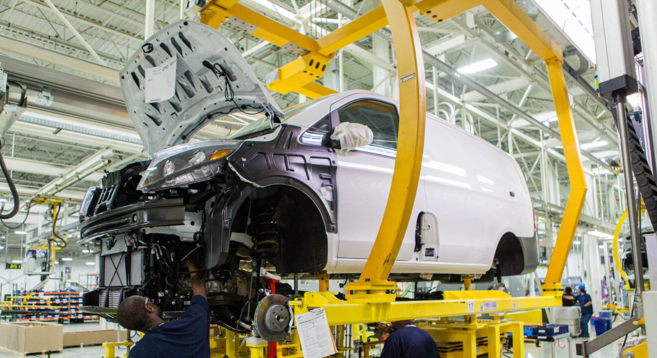 A manufacturing employee works on the body of a car in a factory.