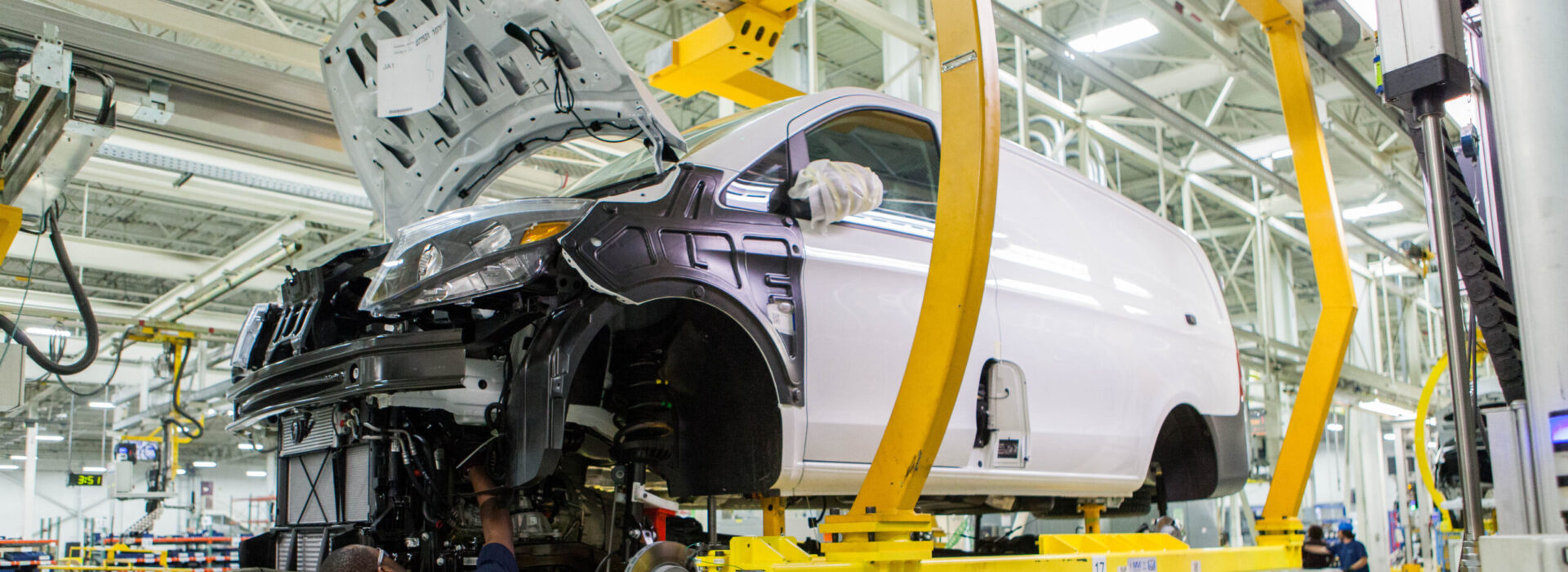 A manufacturing employee works on the body of a car in a factory.