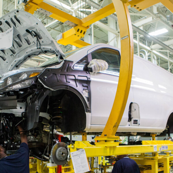 A manufacturing employee works on the body of a car in a factory.