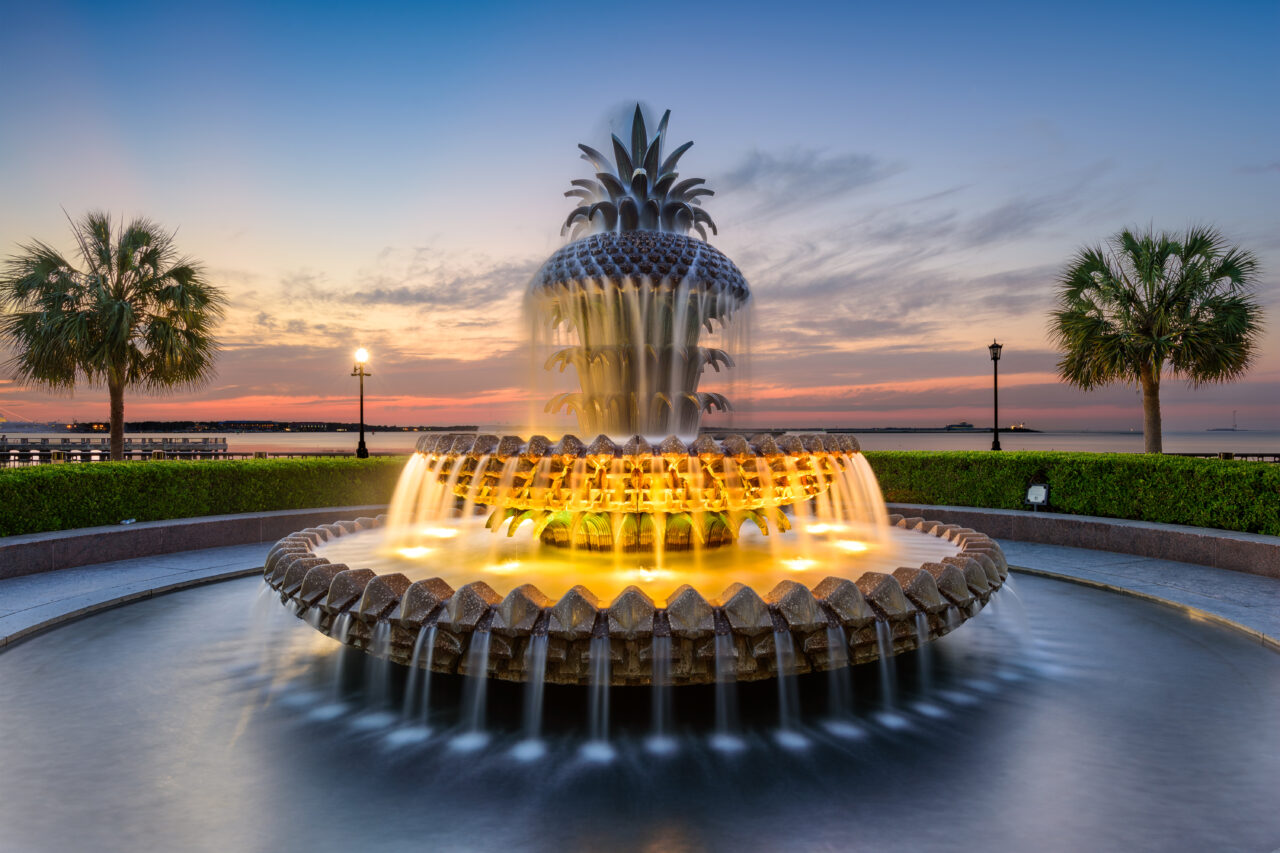 An ornate water fountain lights up at dusk.