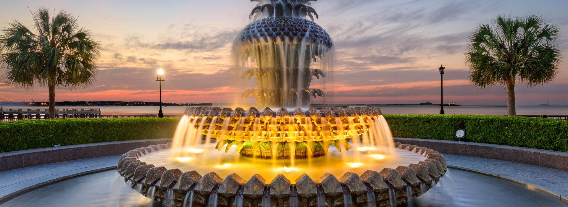 An ornate water fountain lights up at dusk.