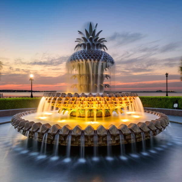 An ornate water fountain lights up at dusk.