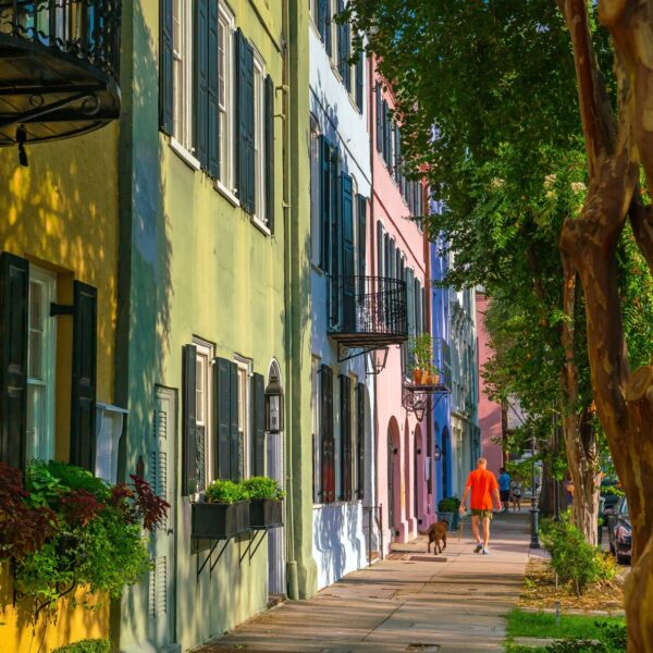 A rman walks his dog in front of a row of colorful townhouses in the Charleston region.