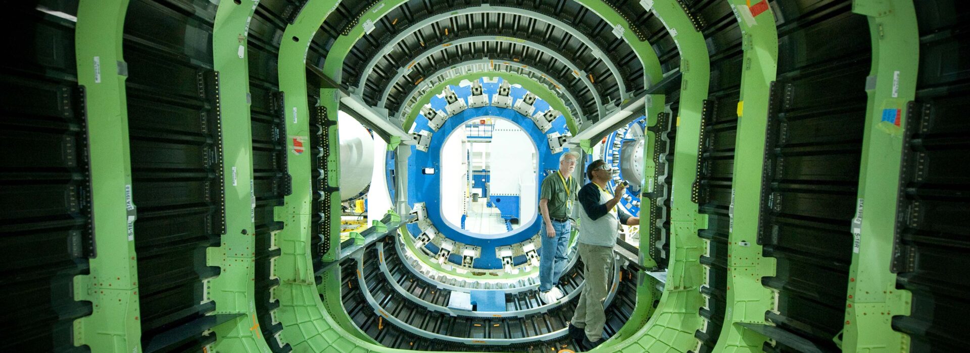 Two men work on the interior of an aerospace vehicle.