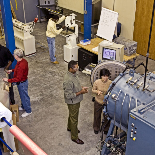 An overhead view of a group of people working in an aircraft training facility together.