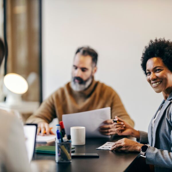 A business woman smiles at her coworker while at a table together.
