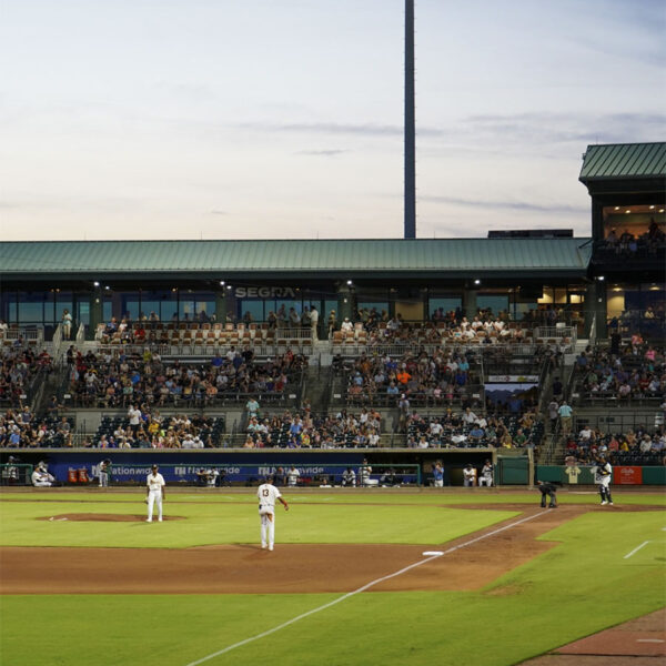 Outfield view of a baseball stadium with players in motion and specators in the background