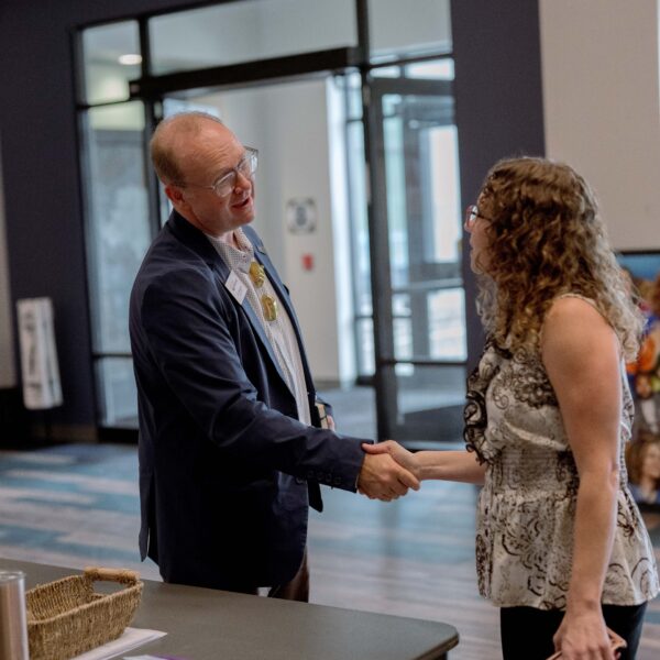 A business man shakes hands with a colleague at an event.